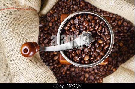 Alte Kaffeemühle mit Kaffeebohnen in Beutel. Stockfoto