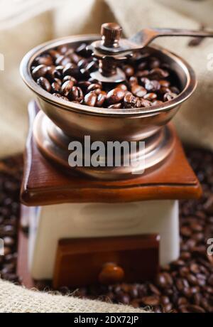 Alte Kaffeemühle mit Kaffeebohnen in Beutel. Stockfoto