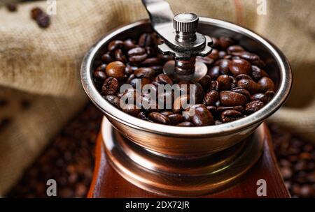 Alte Kaffeemühle mit Kaffeebohnen in Beutel. Stockfoto