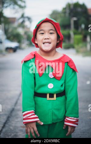 asiatische Kinder tragen roten und grünen Anzug von santa claus Thema steht im Freien Stockfoto