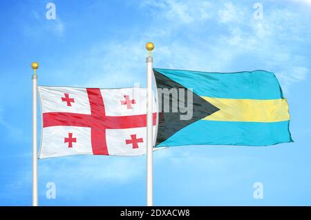 Georgien und Bahamas zwei Flaggen auf Fahnenmasten und blauer Himmel Stockfoto
