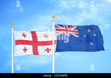 Georgien und Neuseeland zwei Flaggen auf Fahnenmasten und blau Himmel Stockfoto