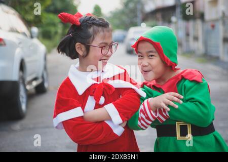 asiatische Mädchen und junge tragen weihnachtsmann Anzug spielend mit Freude im Freien Stockfoto