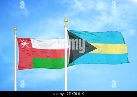Oman und Bahamas zwei Flaggen auf Fahnenmasten und blauer Himmel Stockfoto