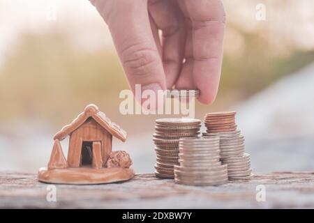 Hand wählen Münzen Stapel Home Modell auf Holz-Tisch Stockfoto