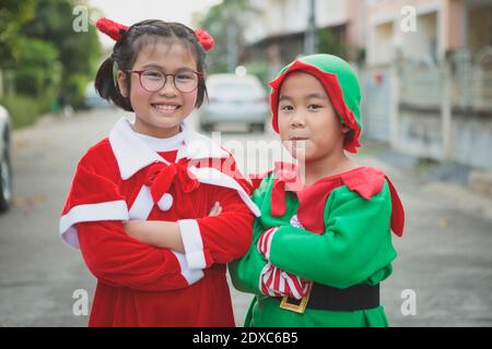 asiatische Mädchen und junge tragen weihnachtsmann Anzug spielend mit Freude im Freien Stockfoto