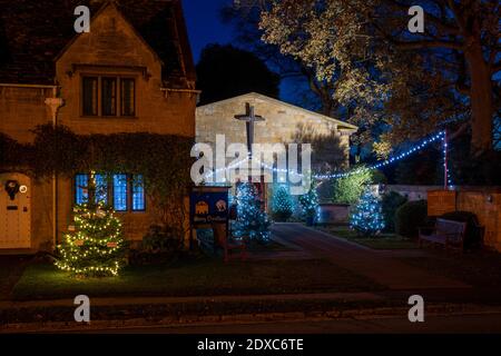 Weihnachtsbäume und Dekorationen in der Nacht vor der vereinigten reformierten Kirche am Broadway. Cotswolds, Gloucestershire, England Stockfoto