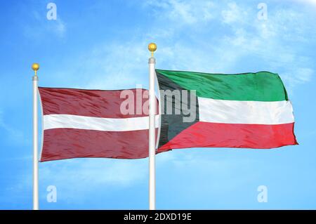 Lettland und Kuwait zwei Flaggen auf Fahnenmasten und blauer Himmel Stockfoto