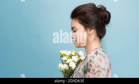 Seitwärts Schuss erfreut attraktive junge Frau hält Frühlingsblumen, Posen über rosa Hintergrund, hat freundliches Lächeln auf Gesicht, hat romantische relationsshi Stockfoto