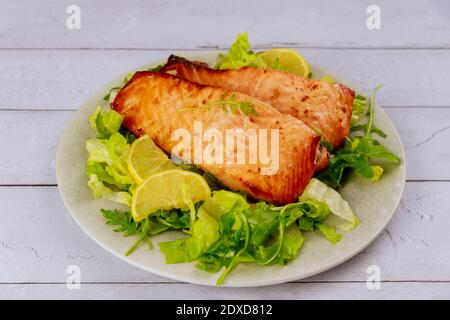 Geröstetes Lachsfilet mit grünem Salat auf grauem Teller. Gesunde Ernährung. Stockfoto