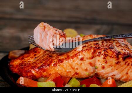 Gegrilltes saftiges Lachsfilet mit gedünstetem Gemüse auf schwarzem Teller. Nahaufnahme. Stockfoto