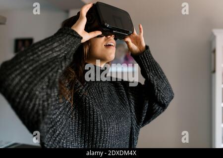 Teenager Mädchen mit Virtual-Reality-Simulator, während zu Hause stehen Stockfoto