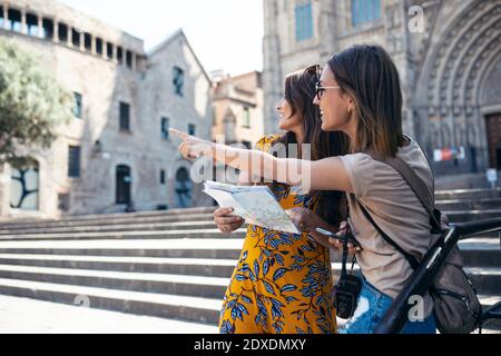 Freunde studieren Karte, während sie am Barcelona Cathedral Square in Barcelona, Katalonien, Spanien stehen Stockfoto