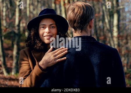 Reife Frau umarmt Mann, während im Wald stehen Stockfoto