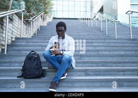 Unternehmer mit Handy, während die Einweg-Tasse auf der Treppe Im Finanzviertel Stockfoto