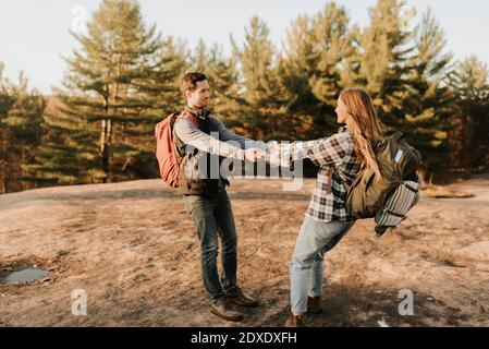 Junges Paar, das sich während der Herbstwanderung die Hände hält Stockfoto