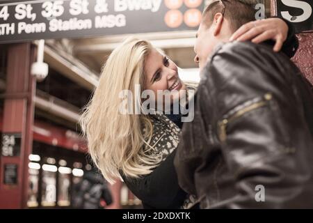 Lächelnde Frau umarmt Mann, während sie an der U-Bahn-Station steht Stockfoto