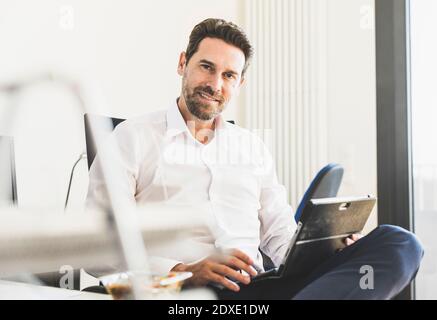 Lächelnder Geschäftsmann mit digitalem Tablet im Büro Stockfoto