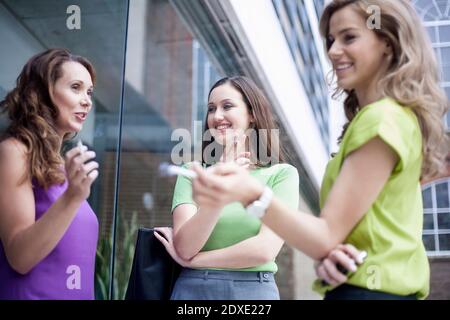 Weibliche Kollegen, die während der Pause vor dem Büro beim Rauchen von Zigaretten klatschen Stockfoto