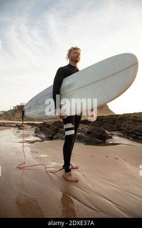 Surfer mit Surfbrett am Strand gegen Himmel Stockfoto