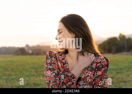 Glückliche Frau umarmt sich gegen den Himmel während des Sonnenuntergangs Stockfoto