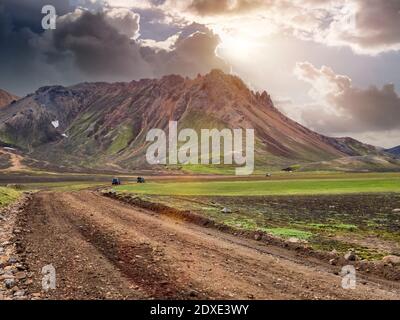 Sonnenuntergang über Offroad-Autos, die auf unbefestigten Straßen in Landmannalaugar fahren Stockfoto