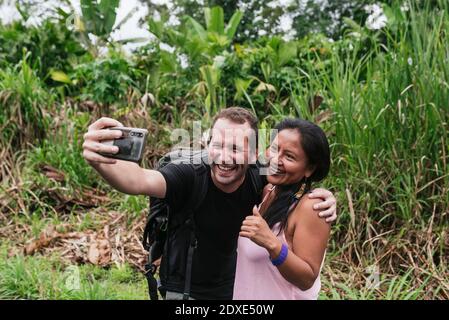 Fröhlicher männlicher Tourist, der Selfie mit Frau in Misahualli, Ecuador macht Stockfoto