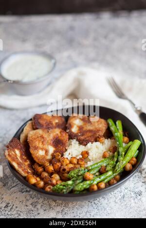 Dipping Sauce und Schüssel Reis mit Kichererbsen, Spargelstielen und gebratenem Halloumi-Käse Stockfoto