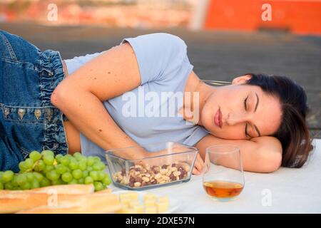 Junge Frau schläft beim Picknick auf dem Dach Stockfoto