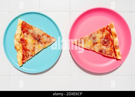 Zwei Scheiben Pizza Margherita auf blauen und rosafarbenen Tellern Stockfoto