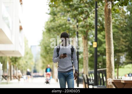 Geschäftsmann mit Handy, während zu Fuß auf dem Weg Stockfoto