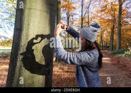 Weibliche Wanderer macht Herzform, während sie in Cannock Chase steht Wald im Herbst Stockfoto