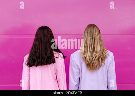 Junge Schwestern schauen auf rosa Wand Stockfoto