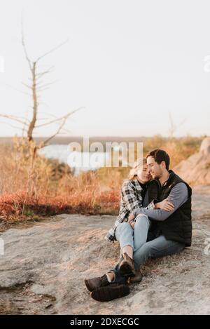 Junges Paar umarmt auf felsiger Oberfläche während Herbstwanderung Stockfoto