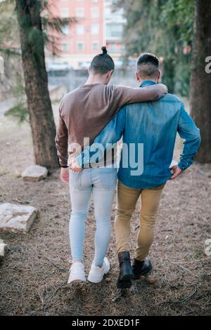 Schwule Paare, die im Park mit den Armen herumlaufen Stockfoto