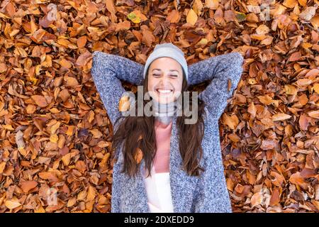 Fröhliche Wanderin mit Händen hinter dem Kopf, die sich darauf legen Herbstlaub im Cannock Chase Wald Stockfoto