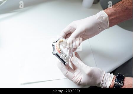 Männlicher Arzt hält während der Untersuchung Prothese auf dem Tisch in der Klinik Stockfoto