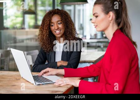 Junge Kolleginnen, die in der Bürokantine am Laptop arbeiten Stockfoto