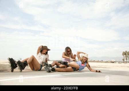 Fröhliche Frauen lachen, während sie auf der Straße am Strand fallen Wochenende Stockfoto