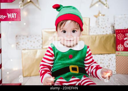 Niedlichen Baby Junge in elf Kostüm spielen, während sitzen an Zuhause während Weihnachten Stockfoto