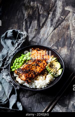 Schüssel Teriyaki Lachs mit Reis, Karottensalat, Edamame-Bohnen, Avocado und Sesam Stockfoto