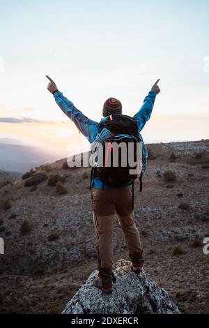 Männlicher Wanderer mit ausgestreckten Armen, der auf einem Felsberg steht Wandern im Urlaub Stockfoto