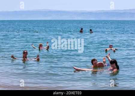 Ausländische Touristen schweben am Toten Meer in Jordanien. Das im Jordan Rift Valley gelegene Wasser ist 9.6 Mal salziger als das Meer. Stockfoto