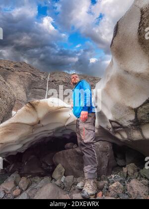 Männlicher Tourist auf Felsen in Langjokull gegen bewölkten Himmel, Island Stockfoto
