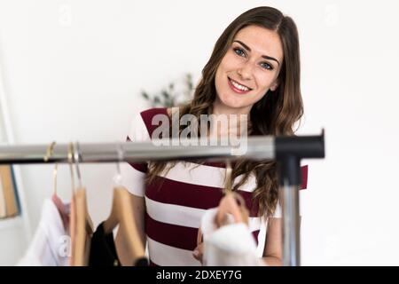 Lächelnde Designerin, die im Studio neben dem Regal steht Stockfoto