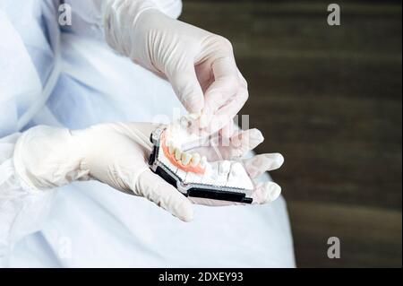 Zahnarzt trägt schützende Arbeitskleidung Herstellung von Prothesen, während in der Klinik stehen Stockfoto