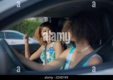 Lächelnde junge Frau, die eine Freundin im Auto sieht Stockfoto
