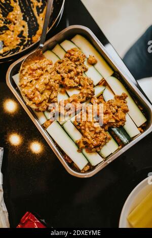 Frau, die Lasagne mit Zucchini zubereitet, während sie in der Küche steht Zu Hause Stockfoto