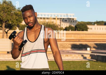 Selbstbewusster Mann beim Training mit Hantel im Park Stockfoto