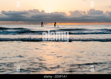 Freunde paddeln auf Mittelmeer gegen Himmel in der Morgendämmerung Stockfoto